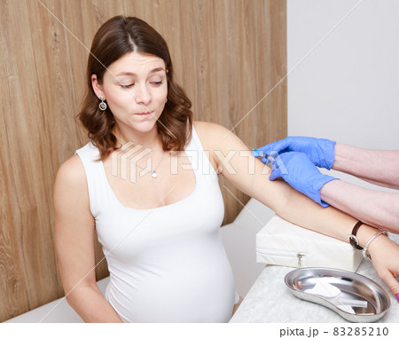 Anxious pregnant woman receiving vaccine injection in arm - pregnancy vaccination concept Anxious pregnant woman receiving vaccine injection in arm - pregnancy vaccination concept 83285210