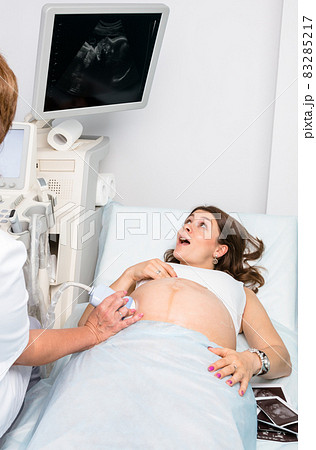Excited pregnant woman looking at sonogram during obstetric ultrasonography Excited pregnant woman looking at sonogram during obstetric ultrasonography 83285217