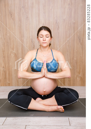Pregnant woman doing yoga exercise meditating 83285228
