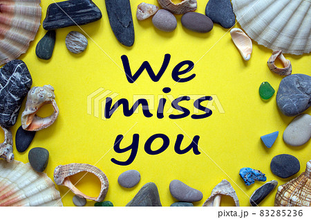 Words 'we miss you' on a beautiful yellow background. Sea stones and seashells. Concept. 83285236