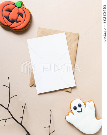 Empty white postcard and craft envelope and Halloween gingerbread cookies - Jack O'Lantern and ghost on beige background 83285465