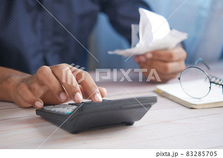 Close up of man hand using calculator and holding bills  83285705