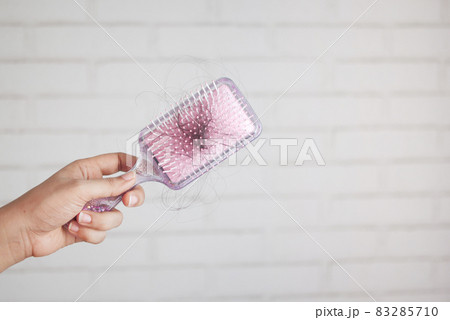women hand hold a brush with lost hair against white wall women hand hold a brush with lost hair against white wall 83285710