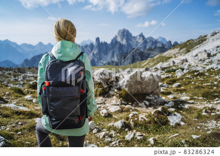 Woman hiker with backpack against Cadini di Misurina mountain group range of Italian Alps, Dolomites, Italy, Europe 83286324