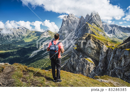 A man with backpack enjoy landscape of Seceda peak in Dolomites Alps, Odle mountain range, South Tyrol, Italy, Europe. Travel vacation concept A man with backpack enjoy landscape of Seceda peak in Dolomites Alps, Odle mountain range, South Tyrol, Italy, Europe. Travel vacation concept 83286385