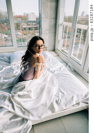 Young happy woman wake up in the morning, sitting on bed and looking on camera.. Young happy woman wake up in the morning, sitting on bed and looking on camera.. 83287184