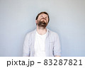 Unhappy, tired Caucasian bearded man in a shirt raised head and looked up, hands down in 83287821