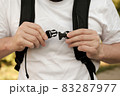 Man is fastening the plastic latch of a city backpack, which is worn on his shoulders. Close-up. 83287977