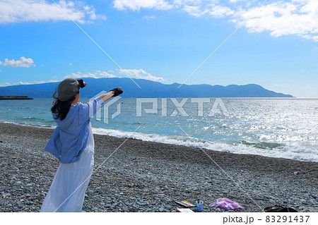 伊豆半島を指さす女性の後ろ姿 83291437