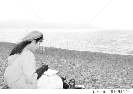 旅先で海をスケッチする画家の女性の姿 83291572