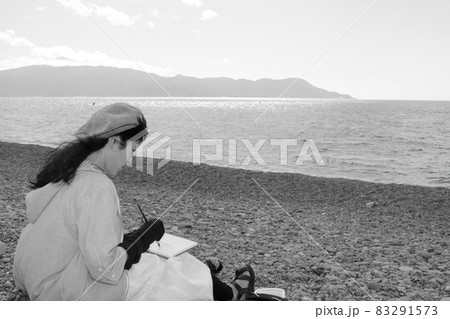 旅先で海をスケッチする画家の女性の姿 83291573