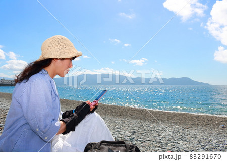 旅先の海辺で携帯を操作する女性の姿 旅先の海辺で携帯を操作する女性の姿 83291670