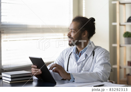 Happy millennial Afro American doctor looking at window away 83292313