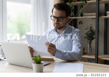 Serious businessman in glasses reading letter, working with correspondence 83292323