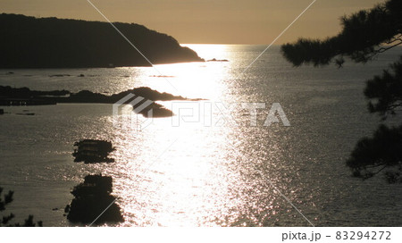 夕陽で照らされる岬と海と松 83294272