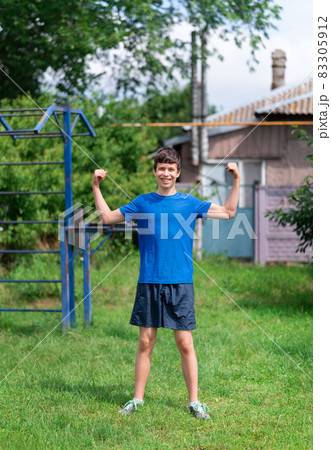 teenage boy exercising outdoors, sports ground in the yard, he posing and does a warm-up, healthy lifestyle 83305912
