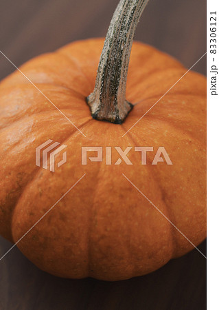 Closeup small orange pumpkin on black walnut table 83306121