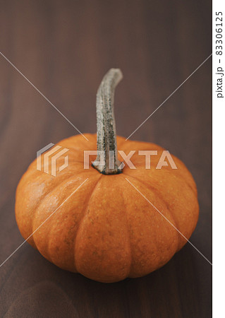 Small orange pumpkin on black walnut table with copy space 83306125