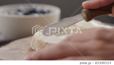 man hand spreading cream cheese on ciabatta man hand spreading cream cheese on ciabatta 83306524