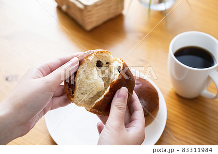 レーズンロールをちぎる女性の手元 83311984
