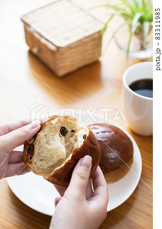 レーズンロールをちぎる女性の手元 83311985