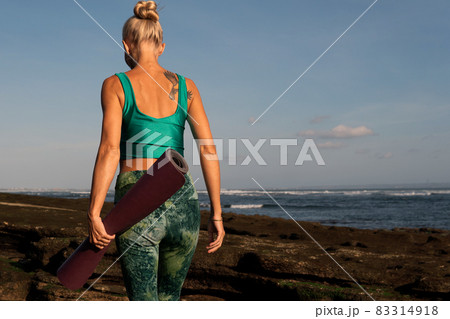 beautiful girl walking on the beach with yoga mat 83314918