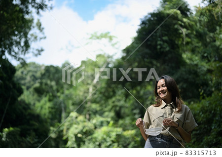 Young woman remove surgical protection mask from her face, surrounded by fresh green forest Young woman remove surgical protection mask from her face, surrounded by fresh green forest 83315713