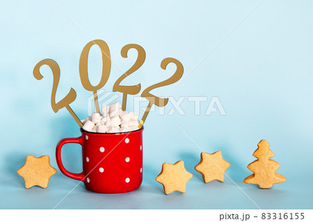 Christmas or New Year 2022 creative concept. Hot chocolate in red mug and golden numbers 2022, copy space 83316155
