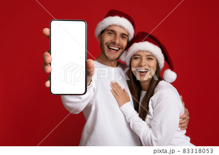 Great App. Happy Young Couple Wearing Santa Hats Showing Blank Smartphone Screen Great App. Happy Young Couple Wearing Santa Hats Showing Blank Smartphone Screen 83318053