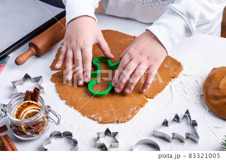Making gingerbread cookies, child cuts dough with Christmas mold on table, horizontal Making gingerbread cookies, child cuts dough with Christmas mold on table, horizontal 83321005