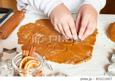 Making gingerbread cookies. Child cuts dough with Christmas mold on table, horizontal 83321007