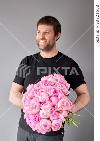 Pink Angel Cheeks peonies in a men hand. Beautiful peony flower for catalog or online store. Floral shop concept . Beautiful fresh cut bouquet. Flowers delivery 83321563
