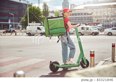 Asian food service courier working on scooter in town 83321846
