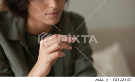 Depressed sad young woman taking off and holding wedding ring Depressed sad young woman taking off and holding wedding ring 83322339