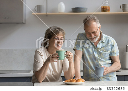 Happy middle aged mature family couple eating breakfast in kitchen. Happy middle aged mature family couple eating breakfast in kitchen. 83322686