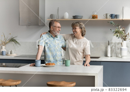 Bonding affectionate older couple talking in kitchen. Bonding affectionate older couple talking in kitchen. 83322694
