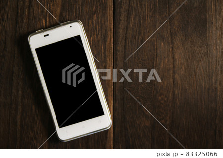 木製のテーブルに置かれたスマホ 83325066