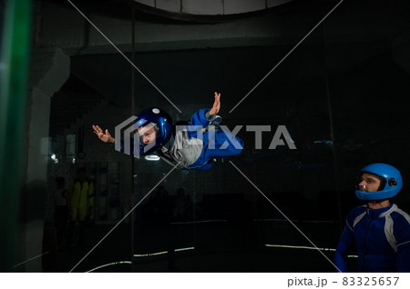 A man teaches a boy to fly in a wind tunnel. 83325657