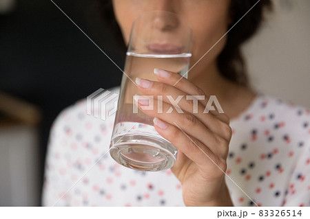 Hand of woman holding glass and drinking fresh cold water Hand of woman holding glass and drinking fresh cold water 83326514