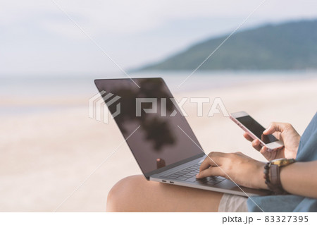 Woman using laptop and smart phone on tropical beach background. Woman using laptop and smart phone on tropical beach background. 83327395