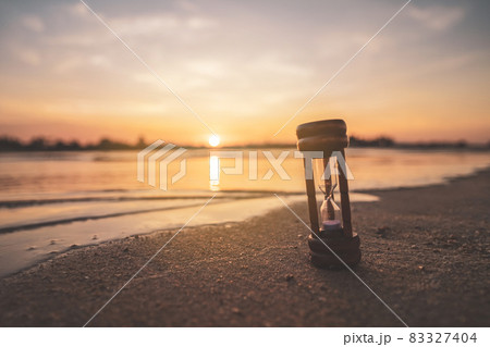 Hourglass on sand beach with sunset sky background. 83327404