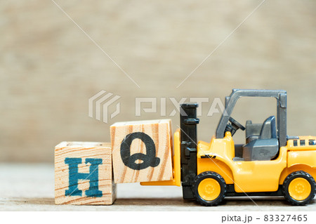 Toy forklift hold letter block q to complete word HQ (Abbreviation of headquarters) on wood background Toy forklift hold letter block q to complete word HQ (Abbreviation of headquarters) on wood background 83327465