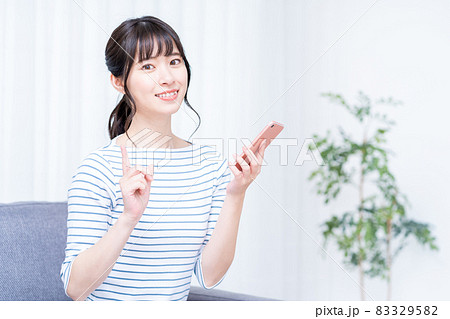 ソファでくつろぎながらスマホを操作する女性。 ソファでくつろぎながらスマホを操作する女性。 83329582