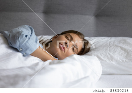Calm relaxed teen girl sleeping in white linen bedclothes 83330213