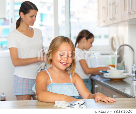 Family working at kitchen, girl cleaning table Family working at kitchen, girl cleaning table 83331020