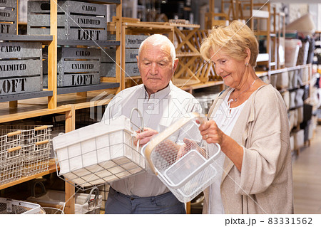 Mature pensioners standing with storage baskets in store Mature pensioners standing with storage baskets in store 83331562