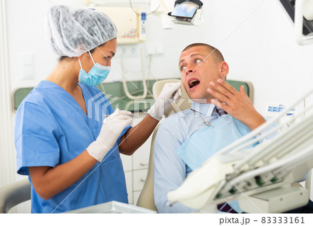 Businessman complains of toothache to dentist 83333161