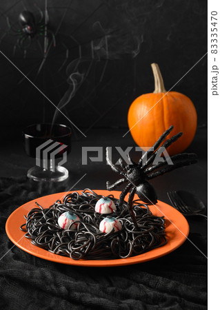 Halloween Italian black pasta decorated funny spiders in orange plate on white. Halloween Italian black pasta decorated funny spiders in orange plate on white. 83335470
