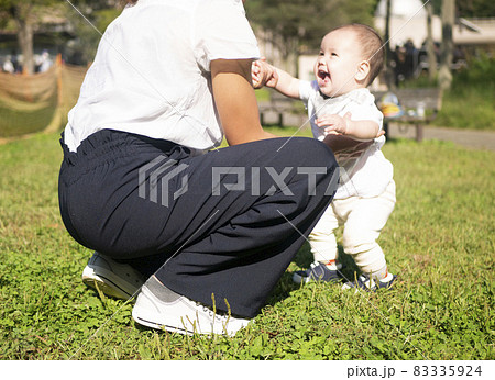 公園で母親と歩く練習をしているハーフの赤ちゃんの写真素材