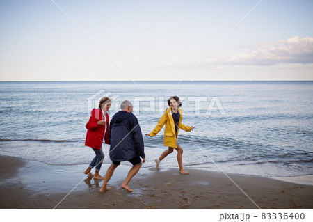 Senior couple and their preteen granddaughter running and having fun on sandy beach. Senior couple and their preteen granddaughter running and having fun on sandy beach. 83336400